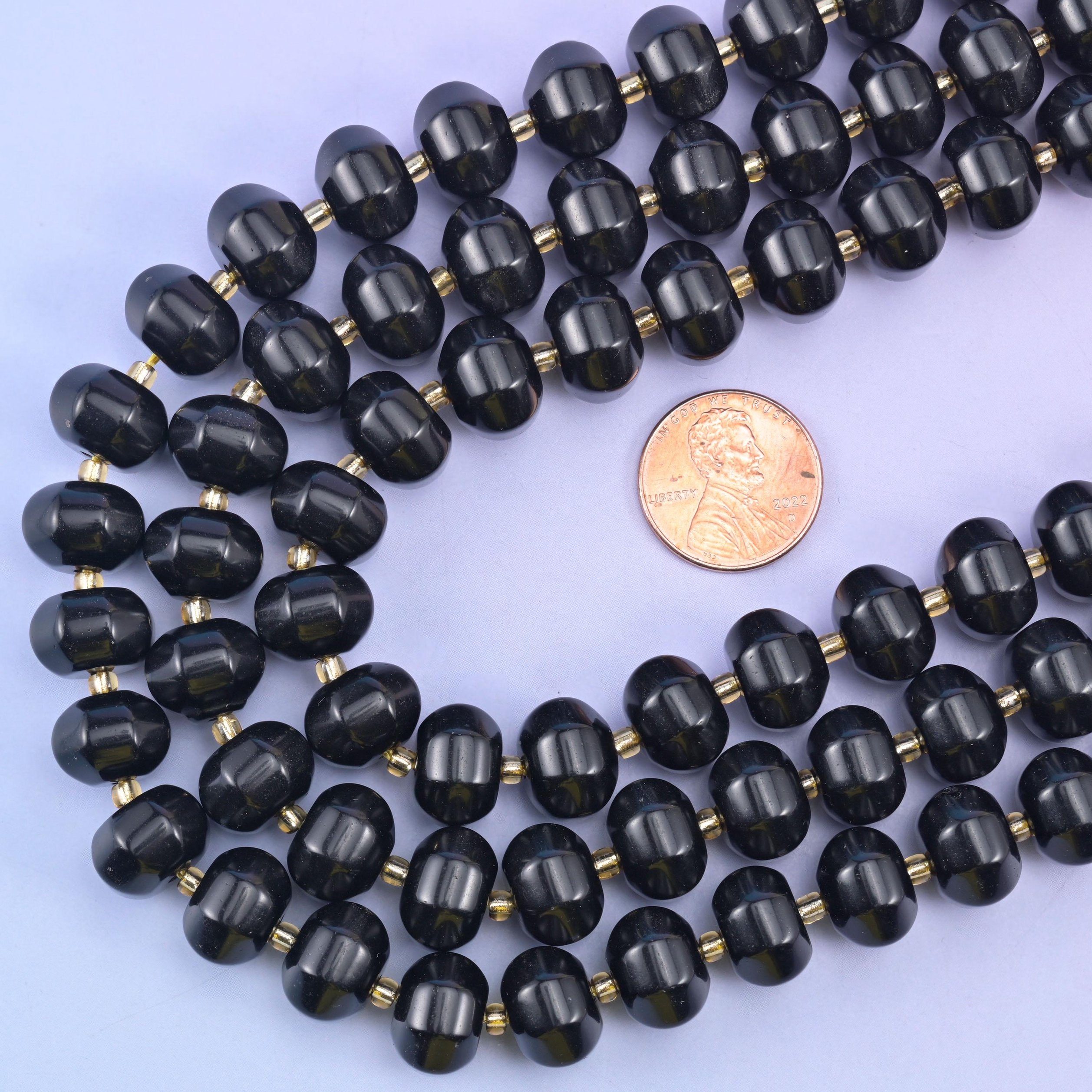 Obsidian pumpkin rondelle strands looped around a US penny to show the 12x8mm bead scale