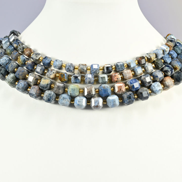 Sunset dumortierite faceted cube bead strands set as a collar on a white display bust, speckled blue, gray and red brown cubes