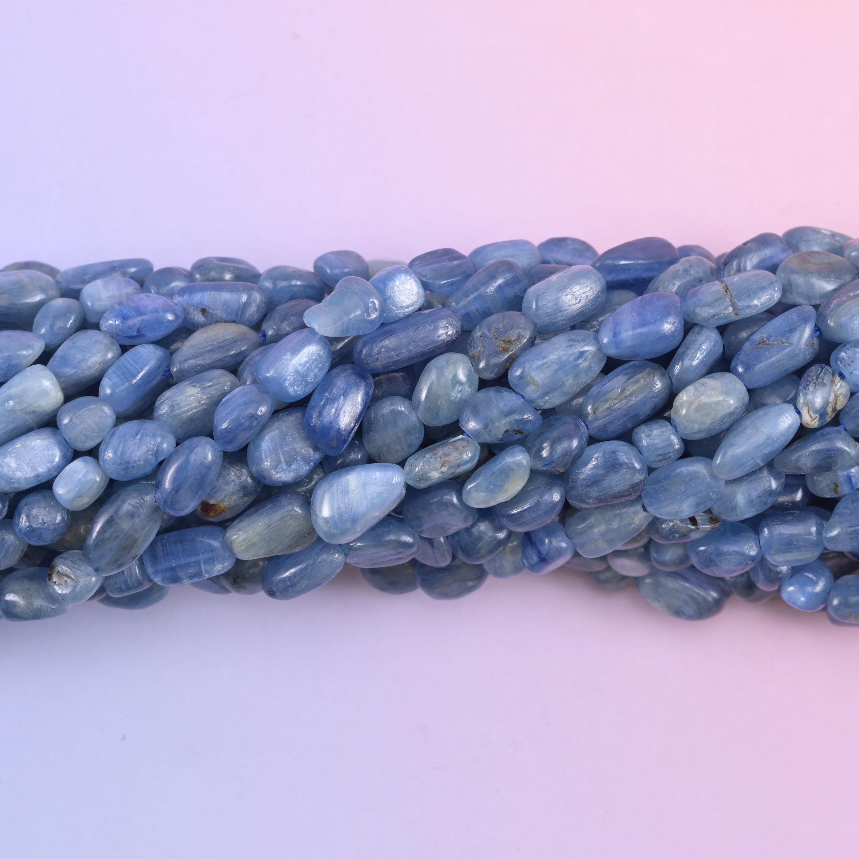 Close macro of polished kyanite pebbles, pearly white fibres running through the blue stone