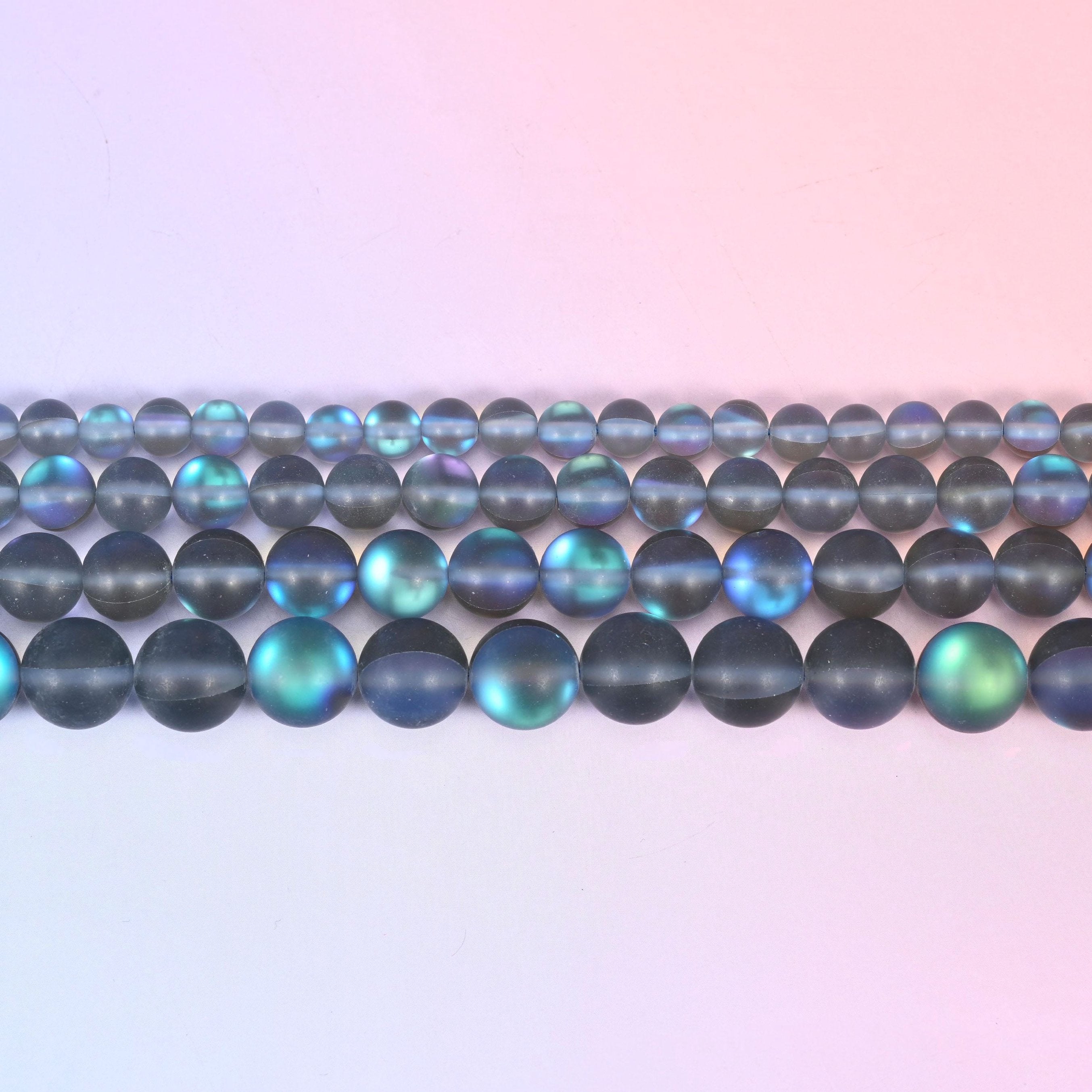 Matte glass beads in frosted smoke grey with a blue-and-green aurora shimmer