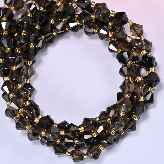 8mm Smoky Quartz faceted bicone beads coiled into a circle on a light lavender background, showing the warm neutral tone of the strand.