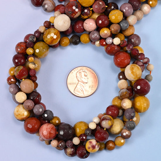 Mookaite faceted round bead strands coiled around a US penny for size reference