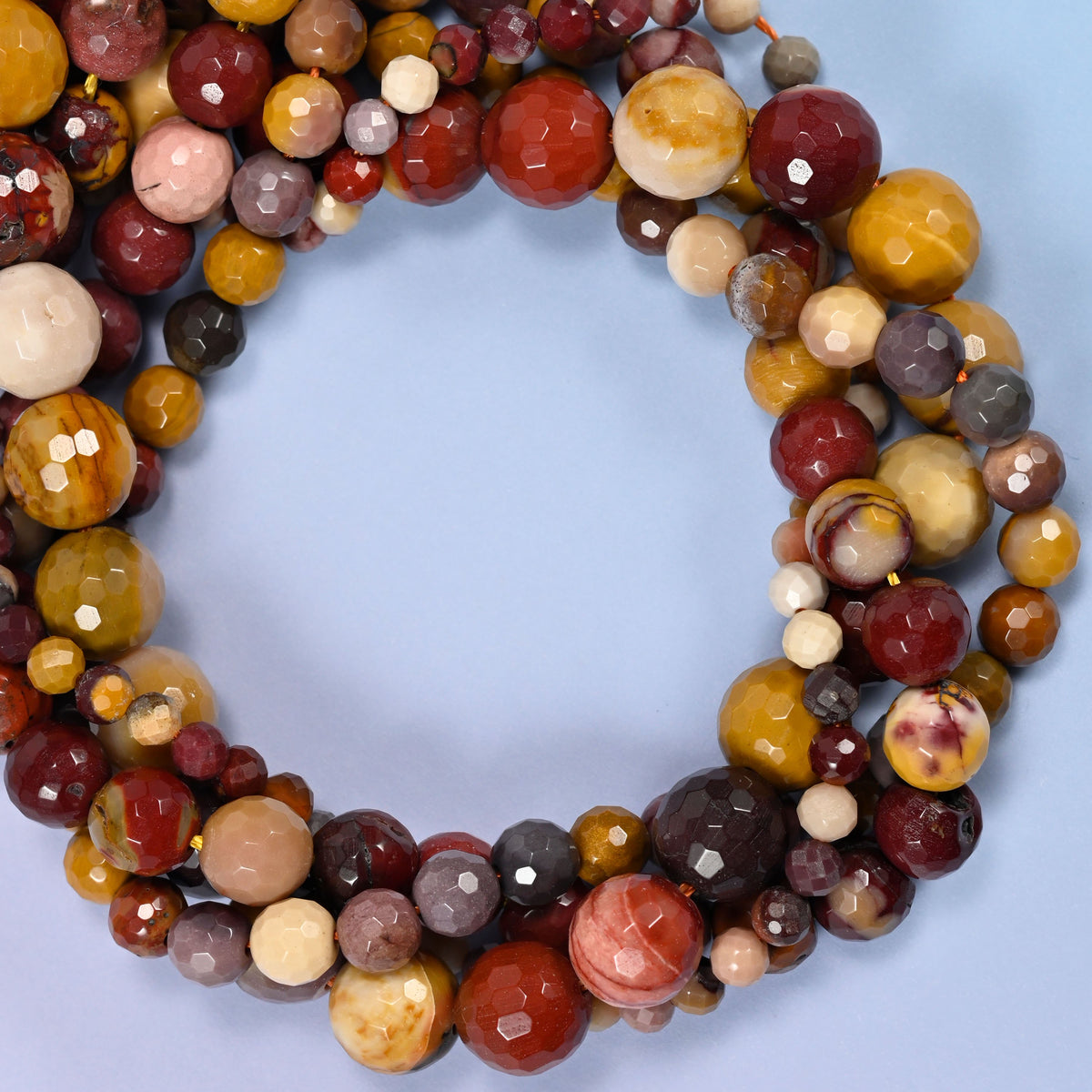 Mookaite faceted round beads, close view of the coiled strands mixing mustard yellow, brick red and cream