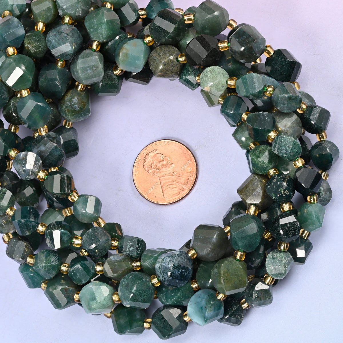 Moss Agate faceted spiral twist bead strands coiled around a US penny for size reference