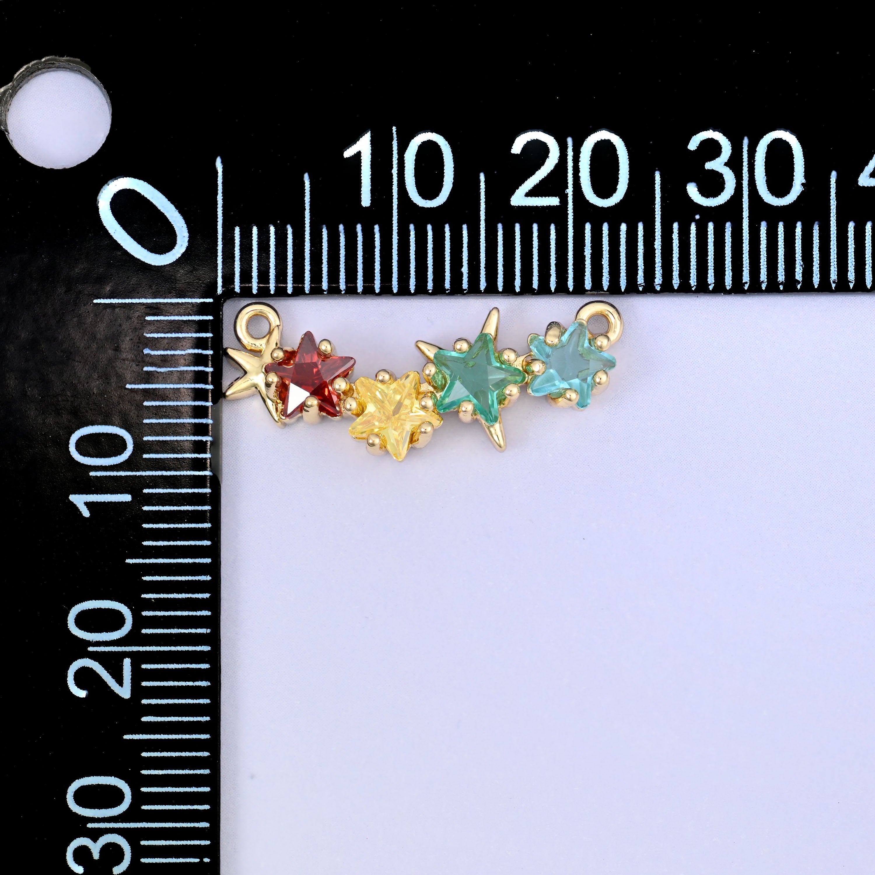A multicolour four star zircon connector photographed beside a millimetre ruler for scale