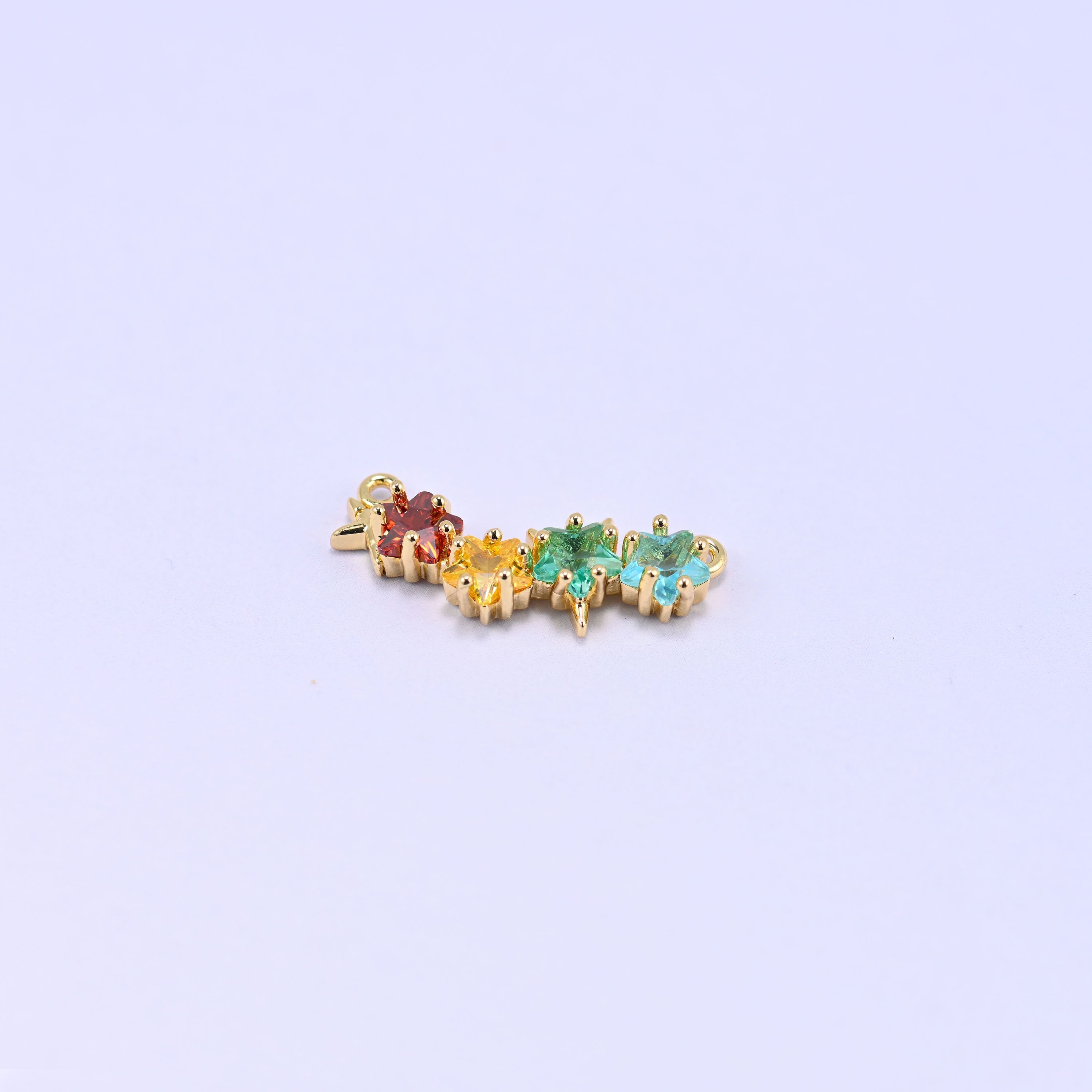 A four star zircon connector set with red, yellow, green and blue stones on a lilac background