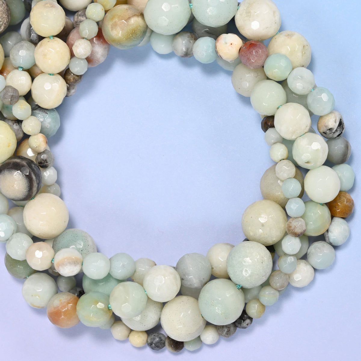 Multicolor Amazonite faceted round beads, close view of the coiled strands mixing seafoam green, cream and grey