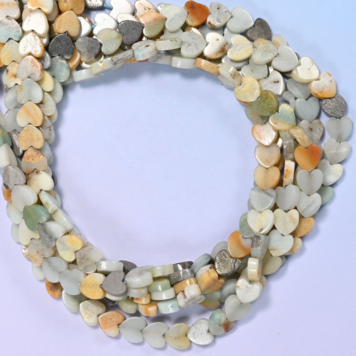 Multicolor Amazonite flat heart beads, close view of the coiled strands mixing seafoam green, cream, tan and grey