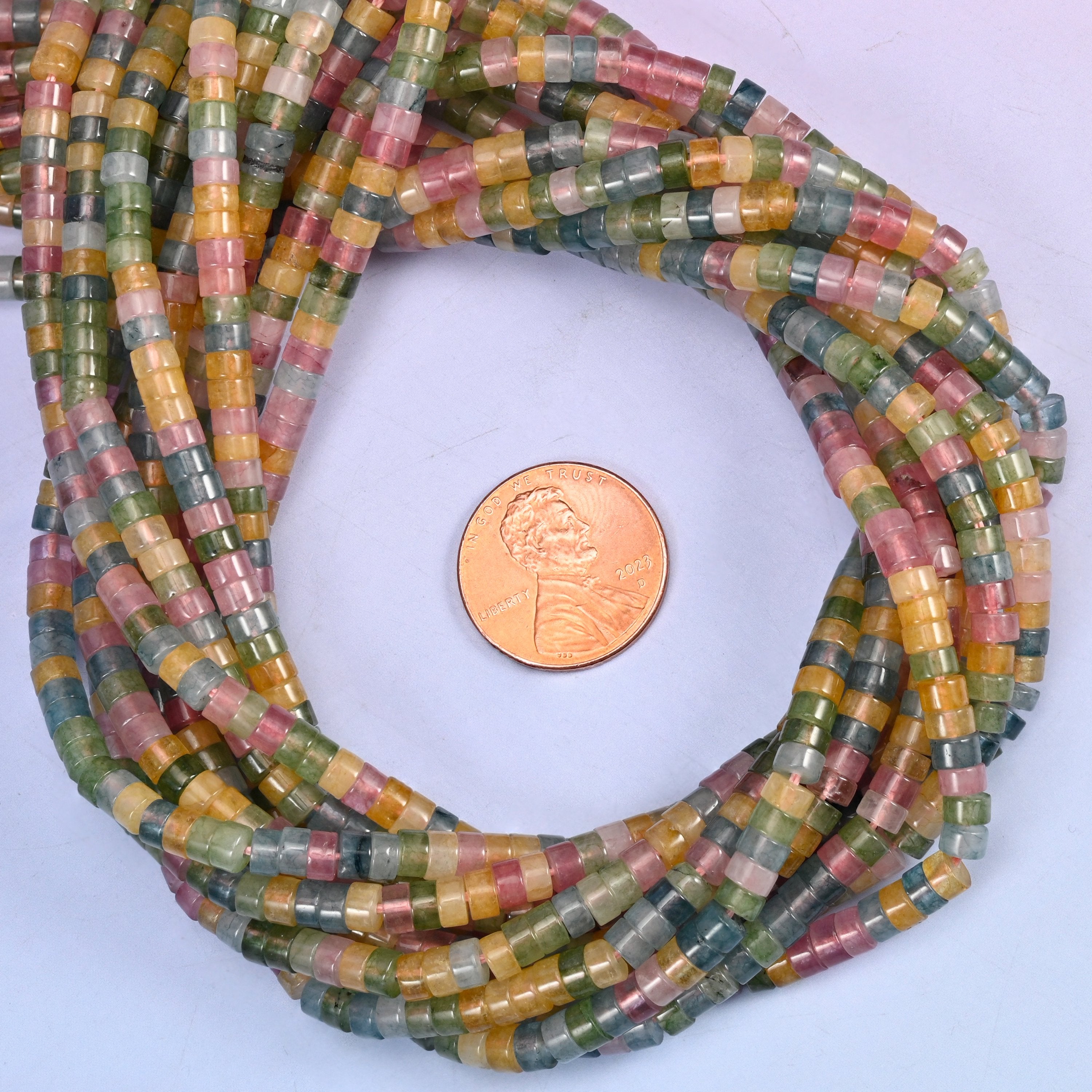 Multicolor Fluorite smooth heishi disc bead strands coiled around a US penny for size reference
