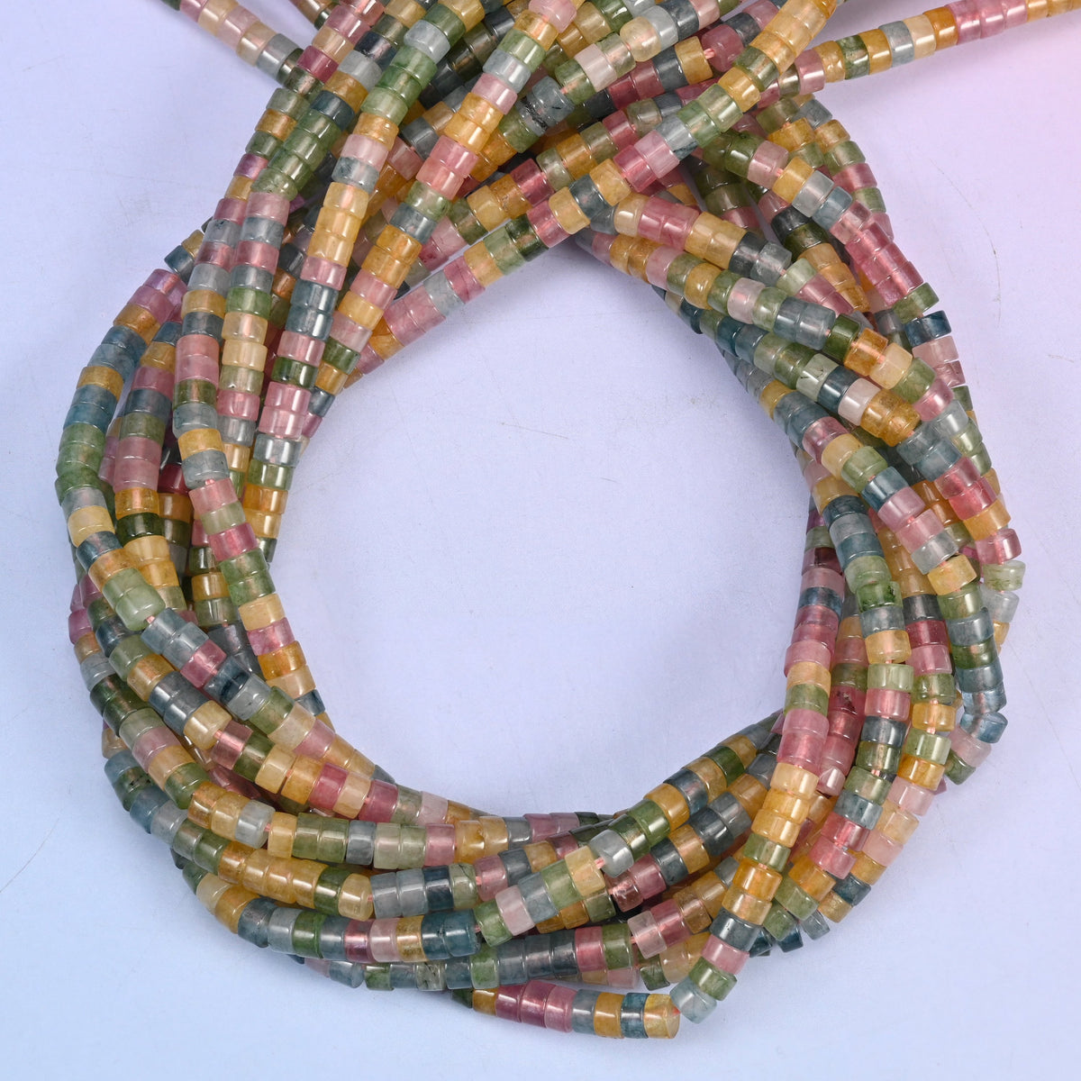 Multicolor Fluorite smooth heishi disc beads, close view of the coiled strands mixing rose pink, amber, sea green and grey