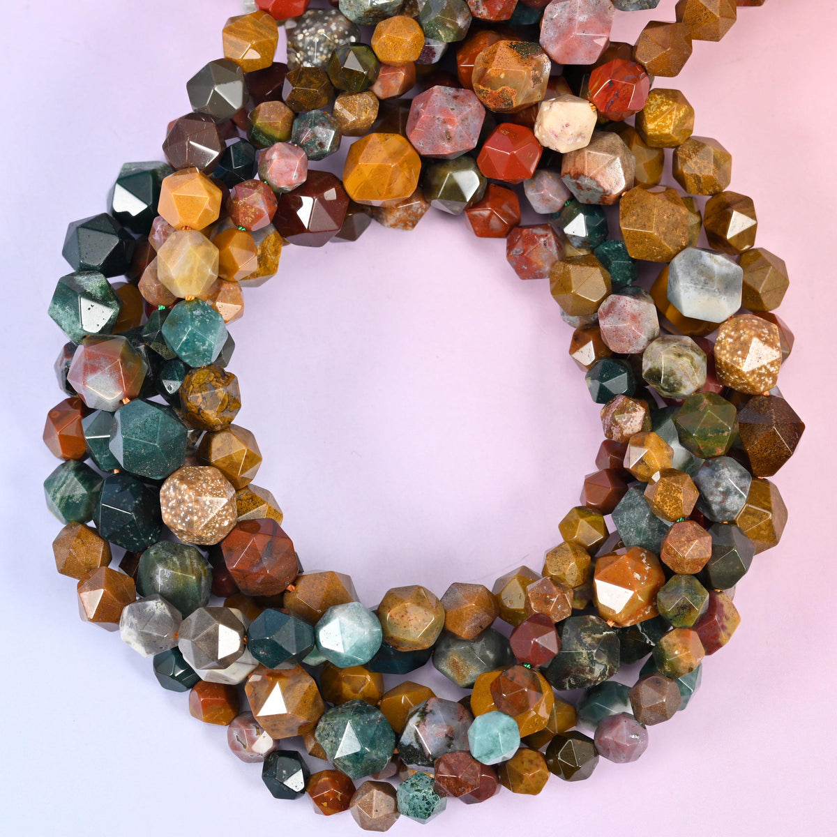 Ocean agate faceted diamond star cut beads, strands coiled into a ring showing the mix of teal, rust, ochre and grey