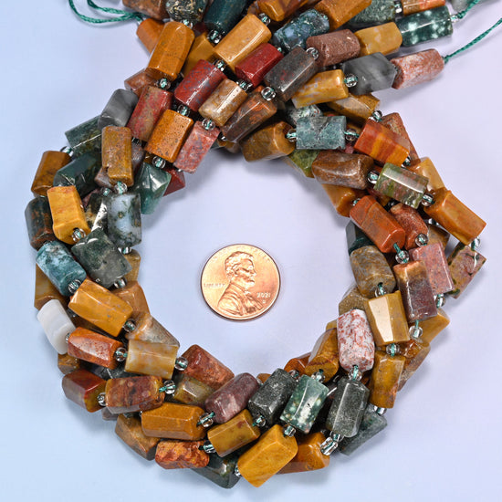 Ocean Jasper faceted tube bead strands coiled around a US penny for size reference
