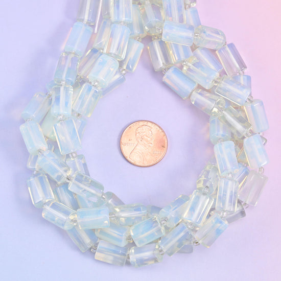 Opalite faceted tube beads coiled around a US penny for size reference, beads about 12x8mm.