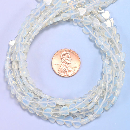 Opalite flat heart bead strands coiled around a US penny for size reference
