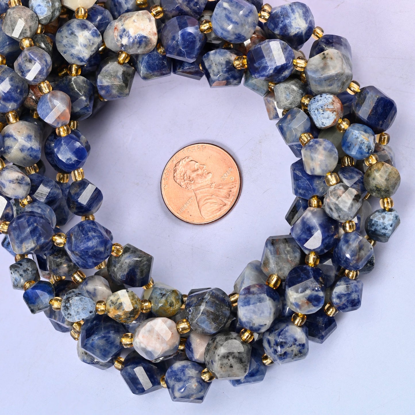 Orange Sodalite faceted spiral twist bead strands coiled around a US penny for size reference