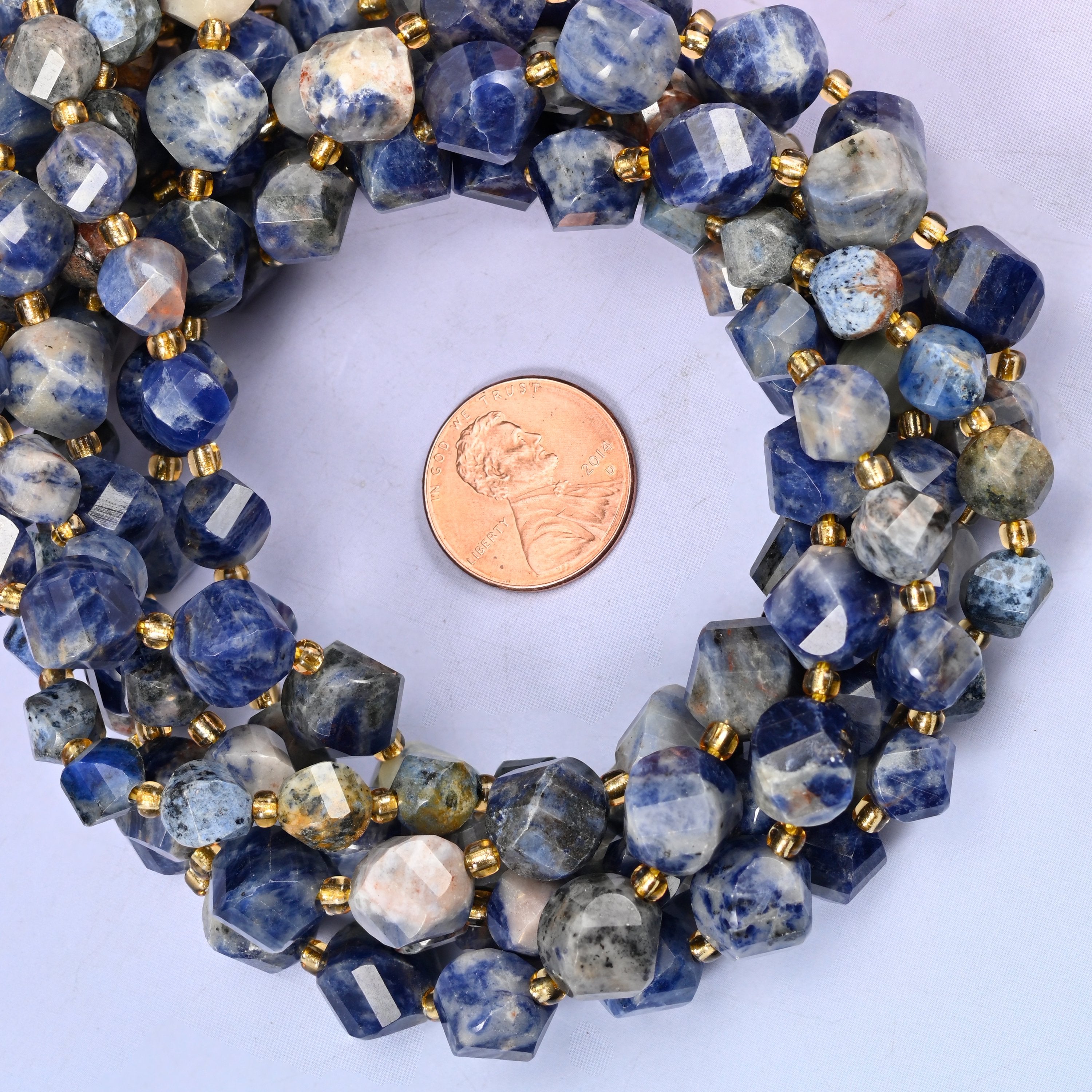 Orange Sodalite faceted spiral twist bead strands coiled around a US penny for size reference