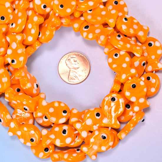 Orange with White Dot Fish glass bead strands coiled around a US penny for size reference