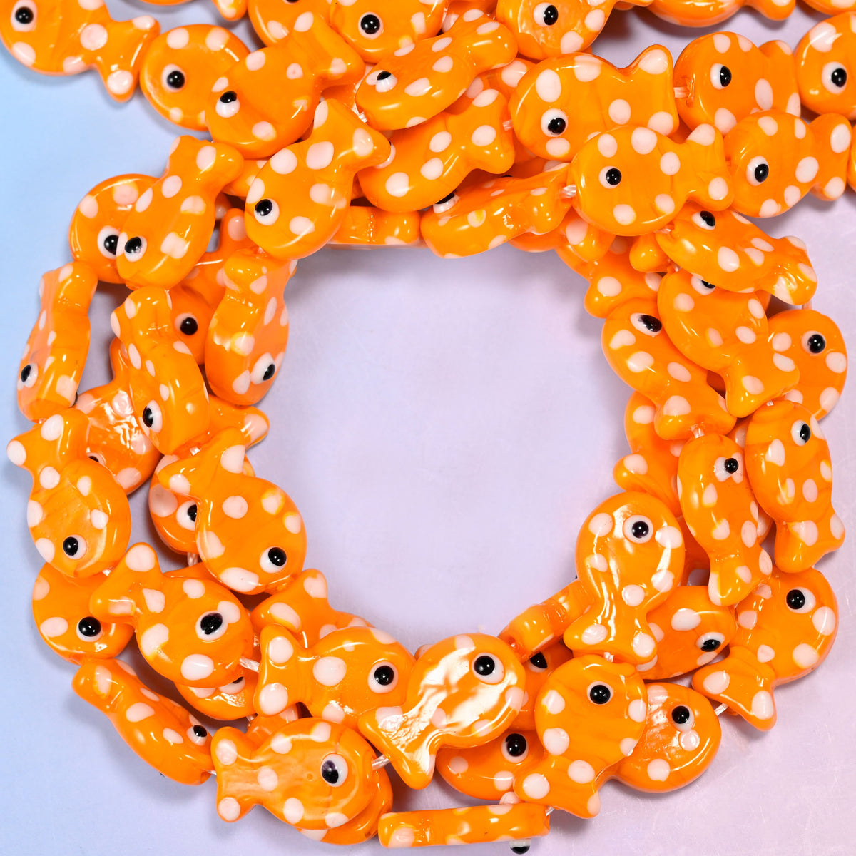 Orange with White Dot Fish glass beads, close view of the coiled strands in bright orange with white spots