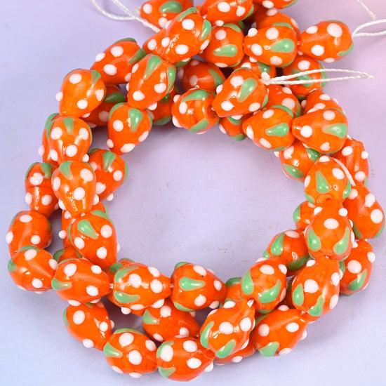 Orange White Dots Strawberry glass beads, close view of the coiled strands in orange with green leaves and white seed dots