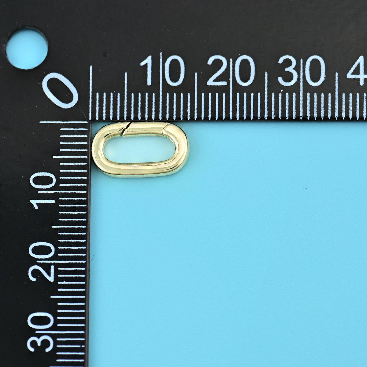 Gold oval carabiner clasp beside a millimetre ruler for scale