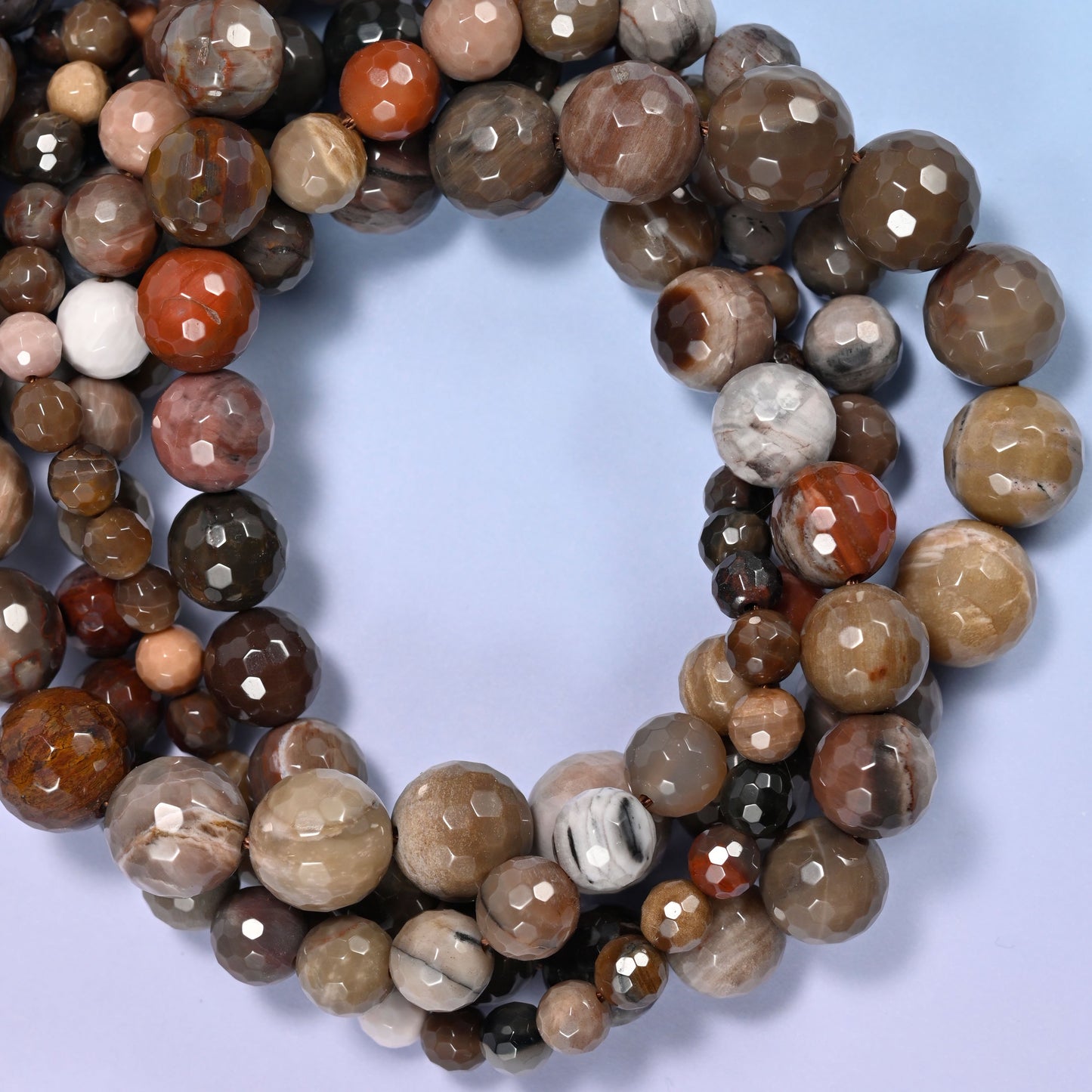 Petrified Wood faceted round beads, close view of the coiled strands mixing brown, grey and cream wood grain