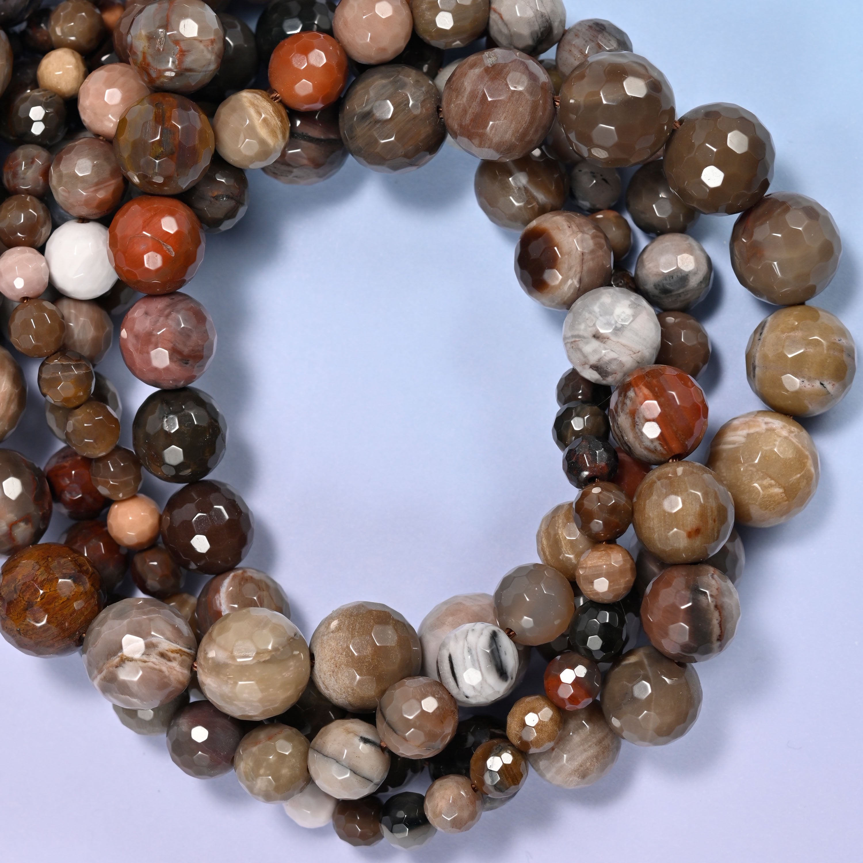 Petrified Wood faceted round beads, close view of the coiled strands mixing brown, grey and cream wood grain