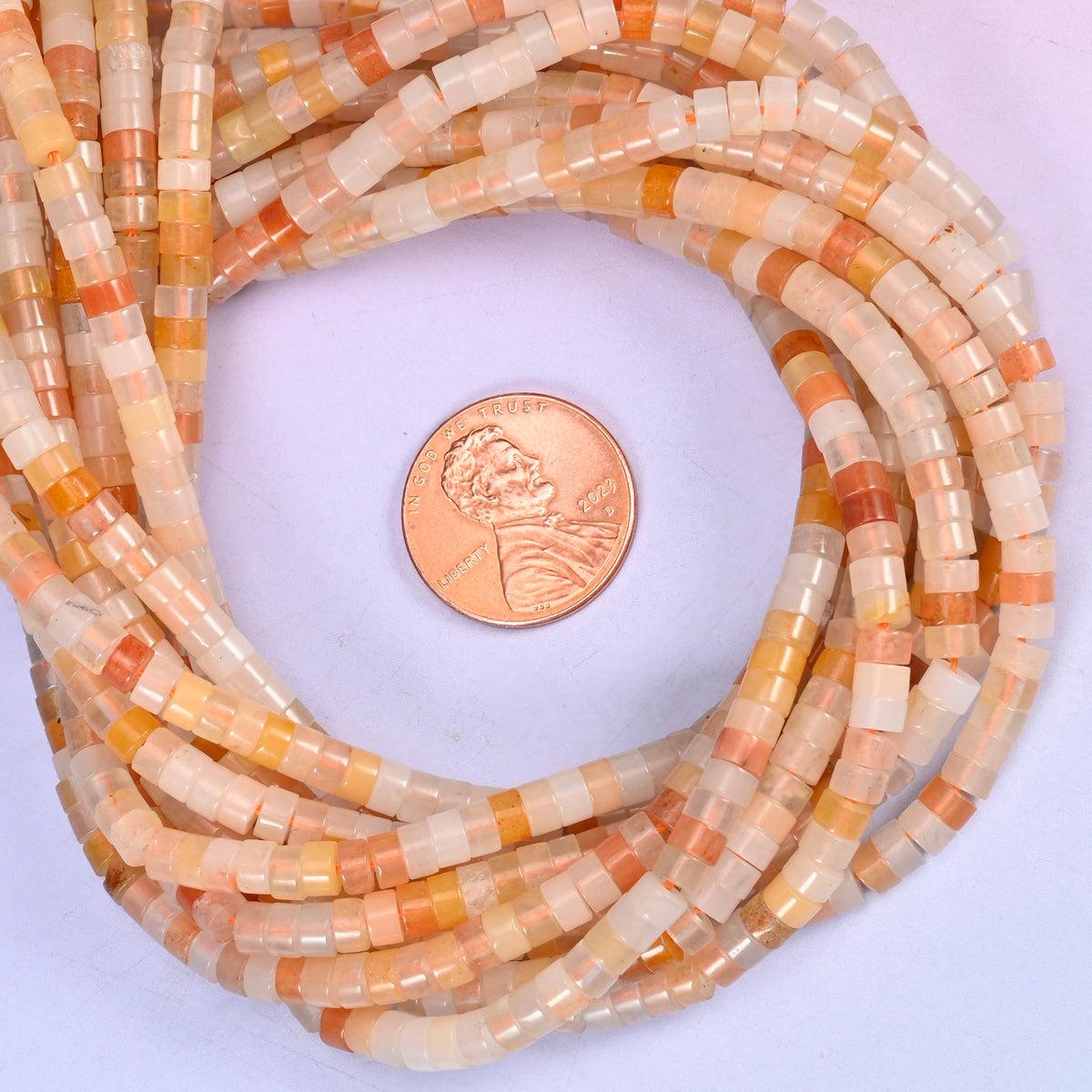 Pink Aventurine smooth heishi disc bead strands coiled around a US penny for size reference
