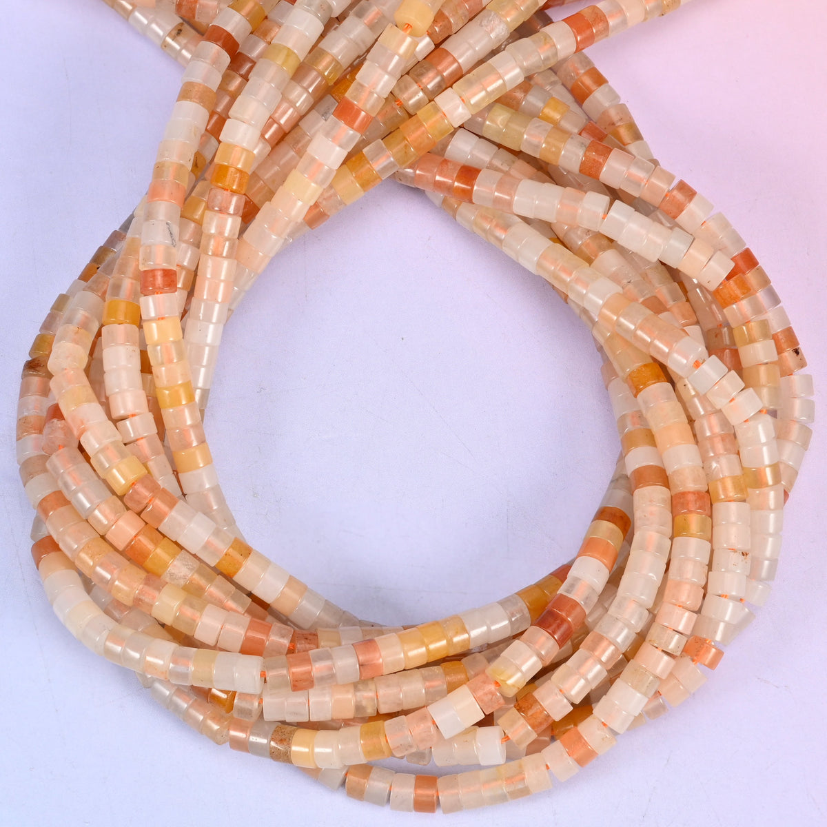 Pink Aventurine smooth heishi disc beads, close view of the coiled strands showing soft peach-pink with cream and apricot banding