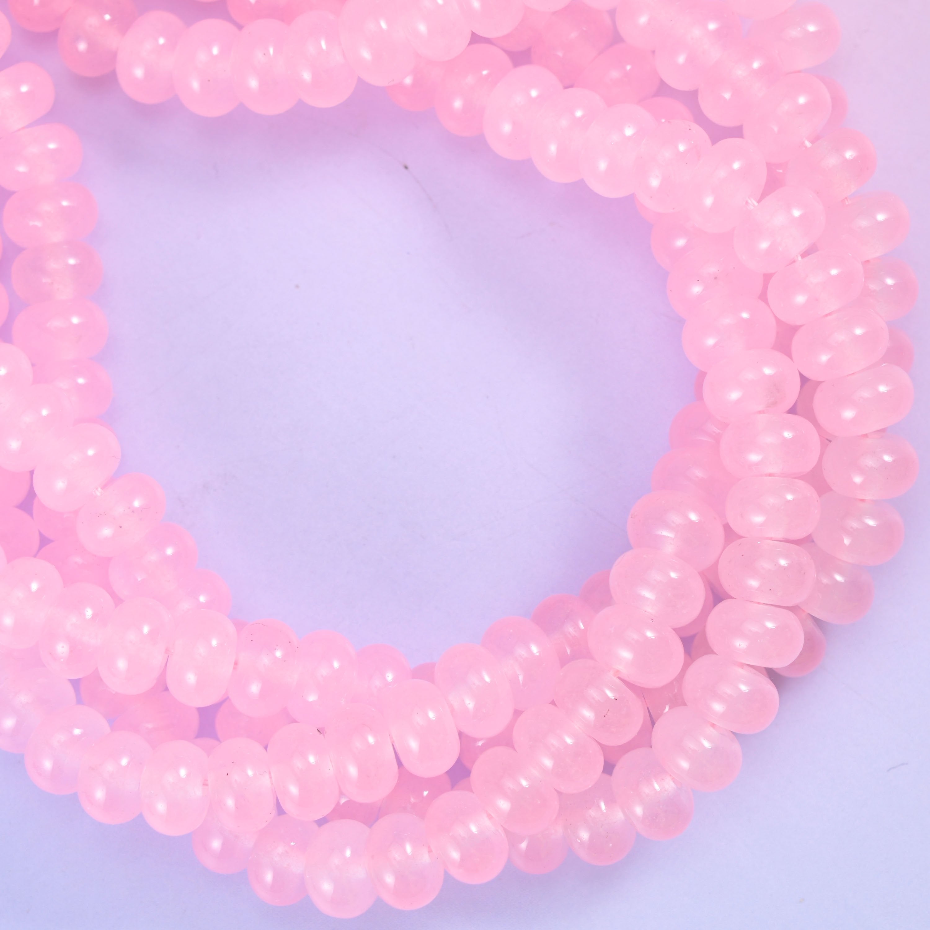 Pink dyed jade smooth rondelle bead strands twisted into a rope coil