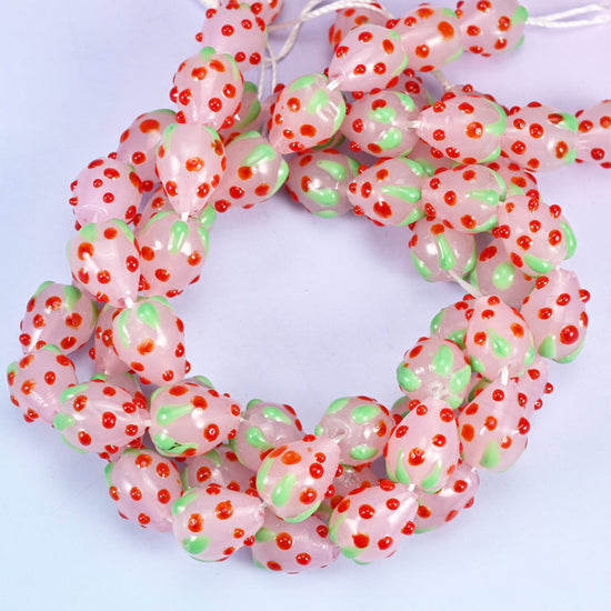 Pink Red Dots Strawberry glass beads, close view of the coiled strands in soft pink with green leaf panels and red seed dots