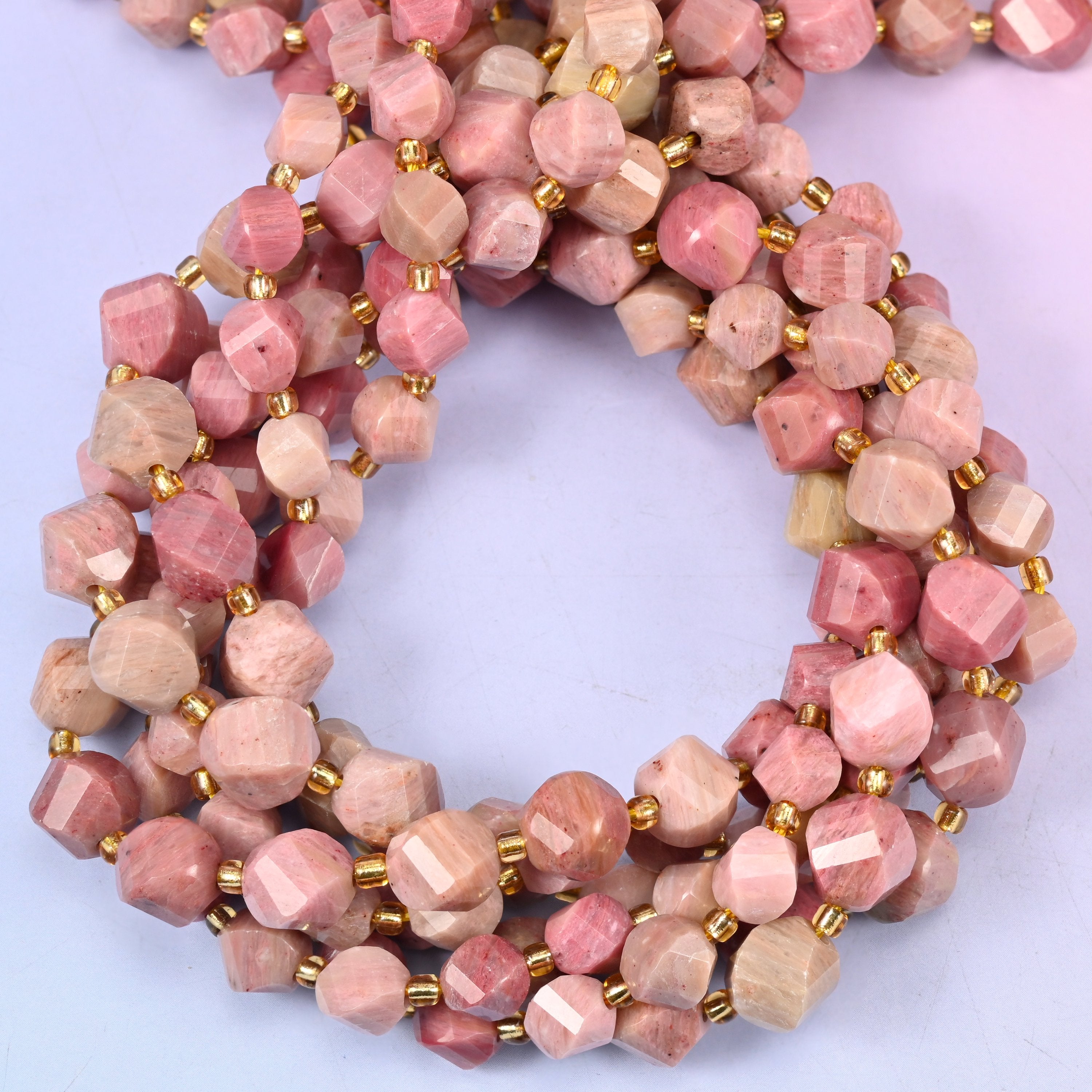 Pink Rhodonite faceted spiral twist beads, close view of the coiled strands showing dusty pink with tan and grey markings