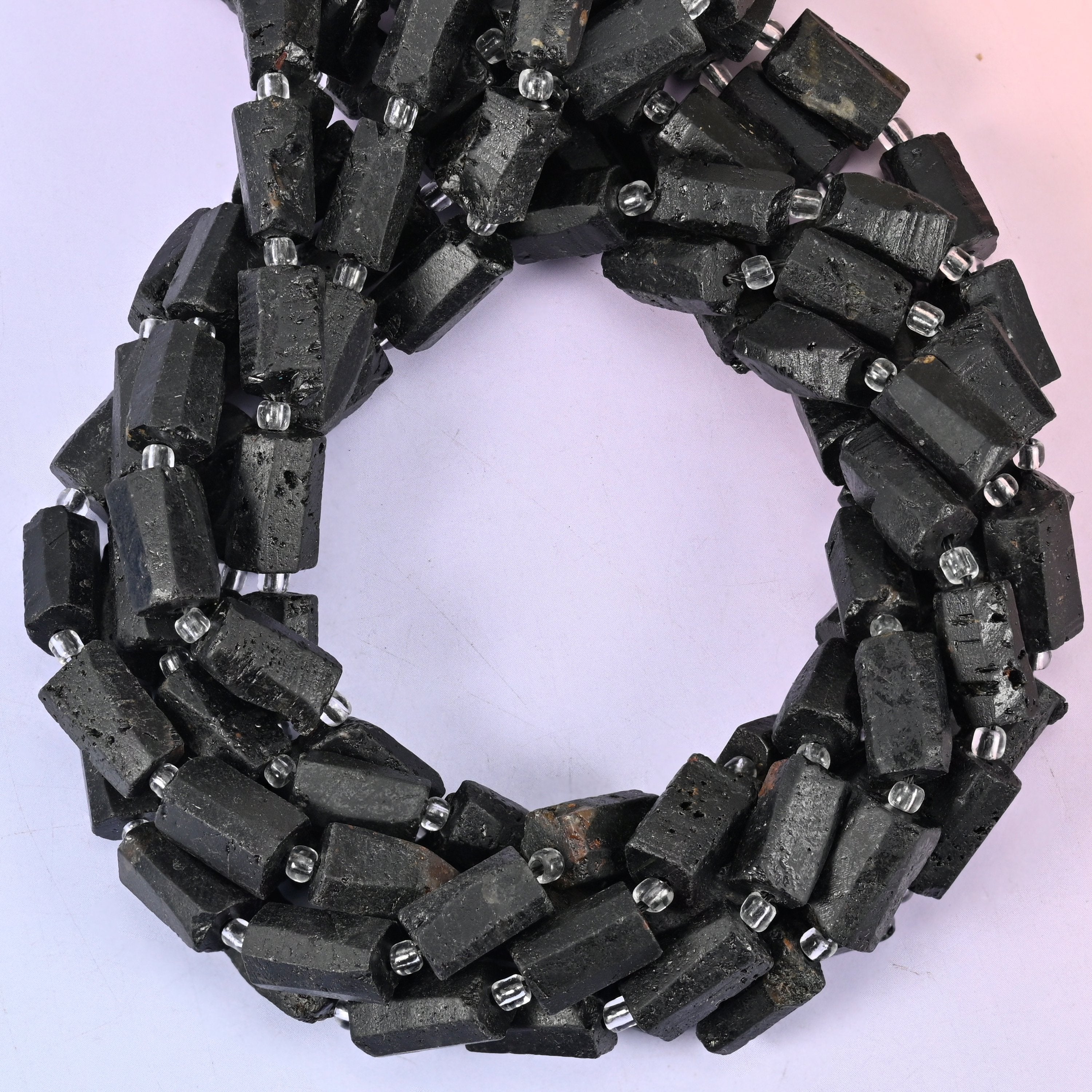Raw Black Tourmaline faceted tube beads, close view of the coiled strands showing matte black with silver spacers