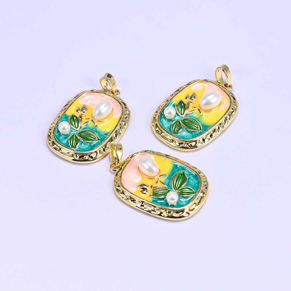Three rectangular tulip enamel pendants with pearl accents grouped on a lilac background