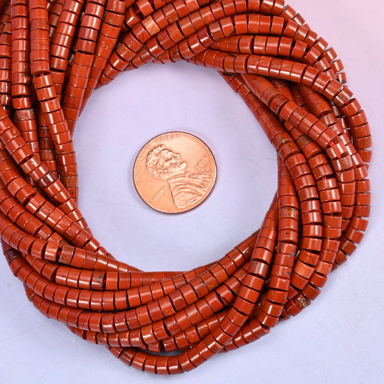 Red Jasper smooth heishi disc bead strands coiled around a US penny for size reference