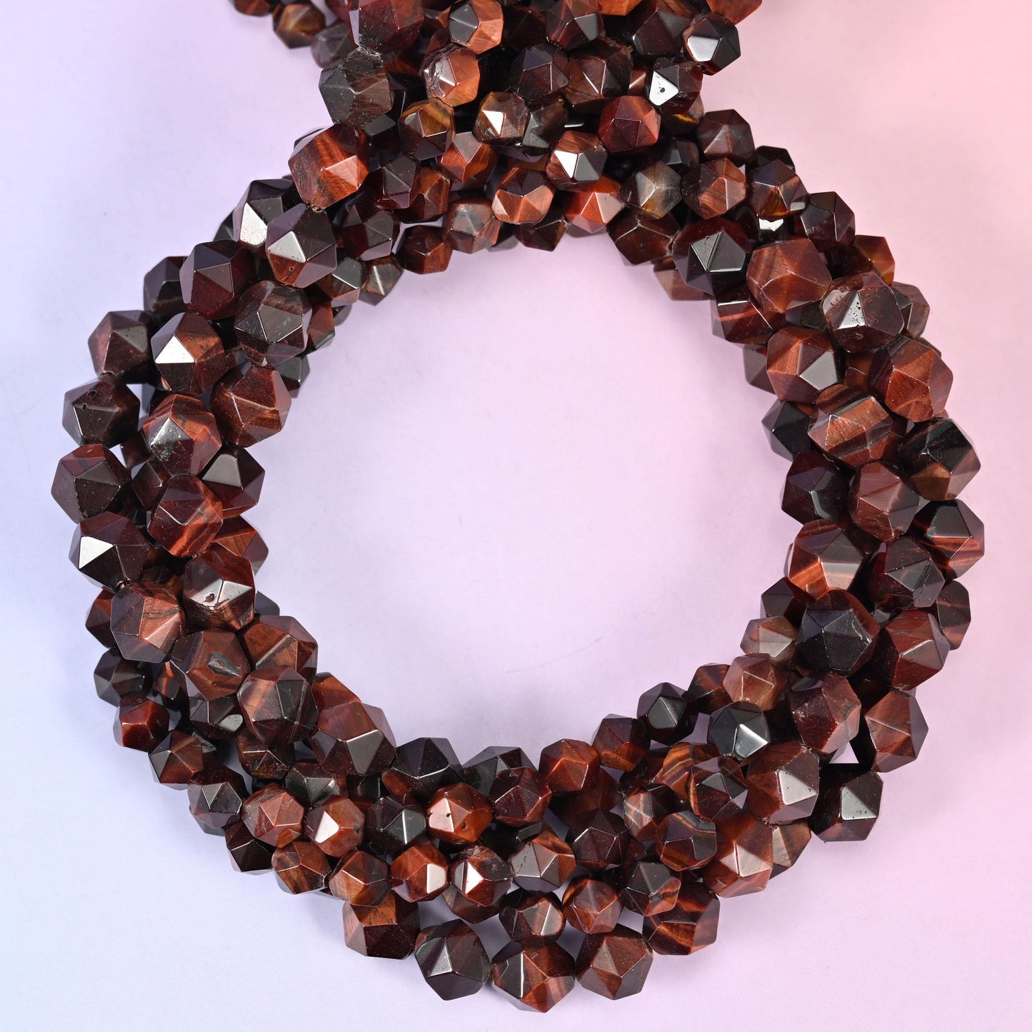 Red tiger eye faceted diamond star cut beads, strands coiled into a ring showing the deep red-brown chatoyant banding
