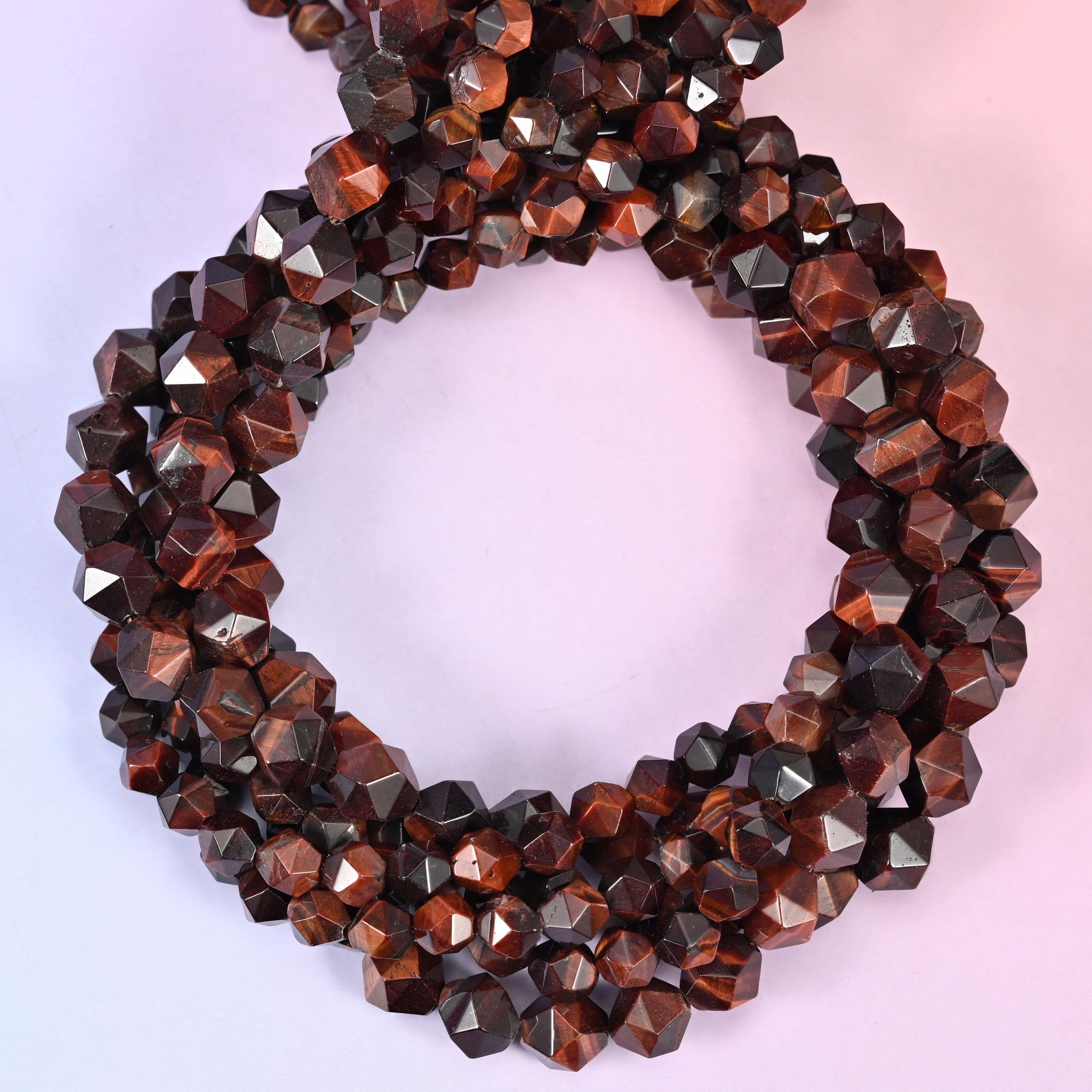 Red tiger eye faceted diamond star cut beads, strands coiled into a ring showing the deep red-brown chatoyant banding