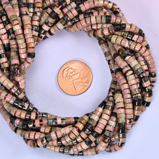 Rhodonite smooth heishi disc bead strands coiled around a US penny for size reference