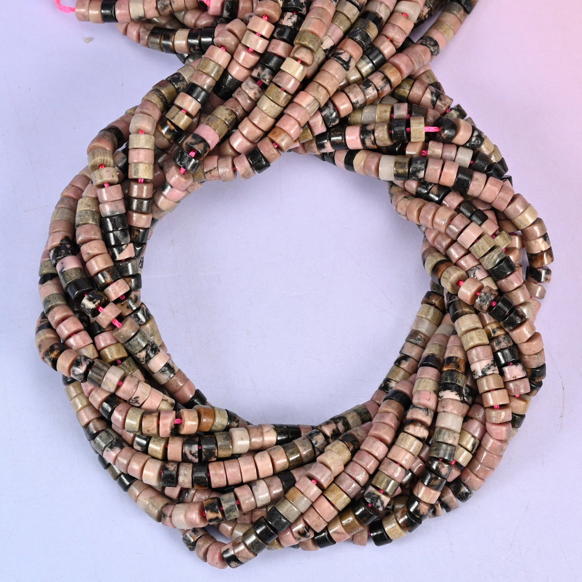 Rhodonite smooth heishi disc beads, close view of the coiled strands showing dusty pink with black and olive markings