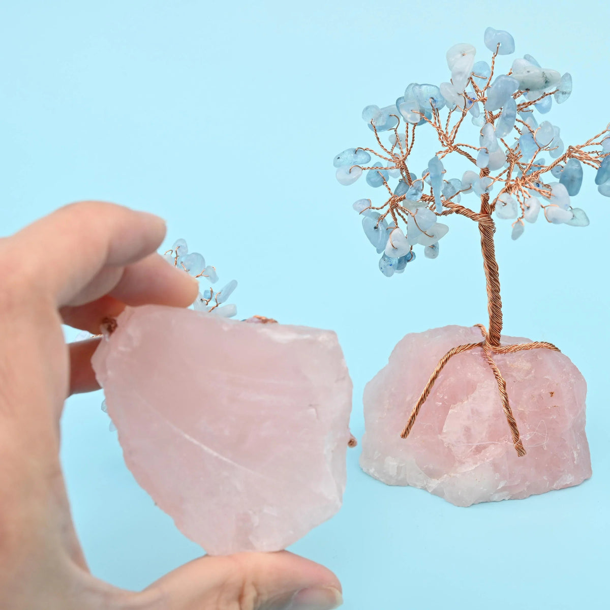 Rose quartz base gemstone tree with copper wire branches, held in a hand to show its 5 inch height