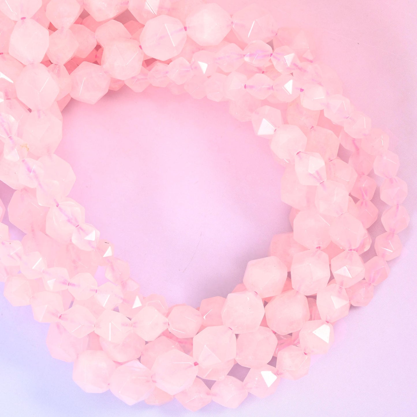 Rose quartz faceted diamond star cut beads, strands coiled into a loop showing the soft frosted pink stone and cut facets