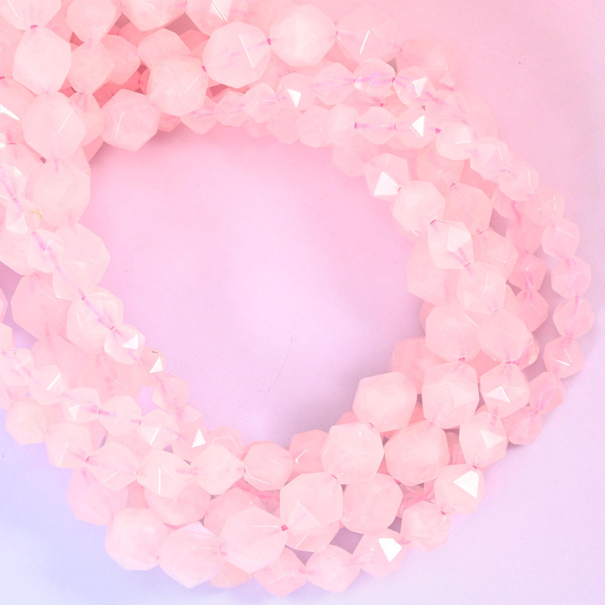 Rose quartz faceted diamond star cut beads, strands coiled into a loop showing the soft frosted pink stone and cut facets