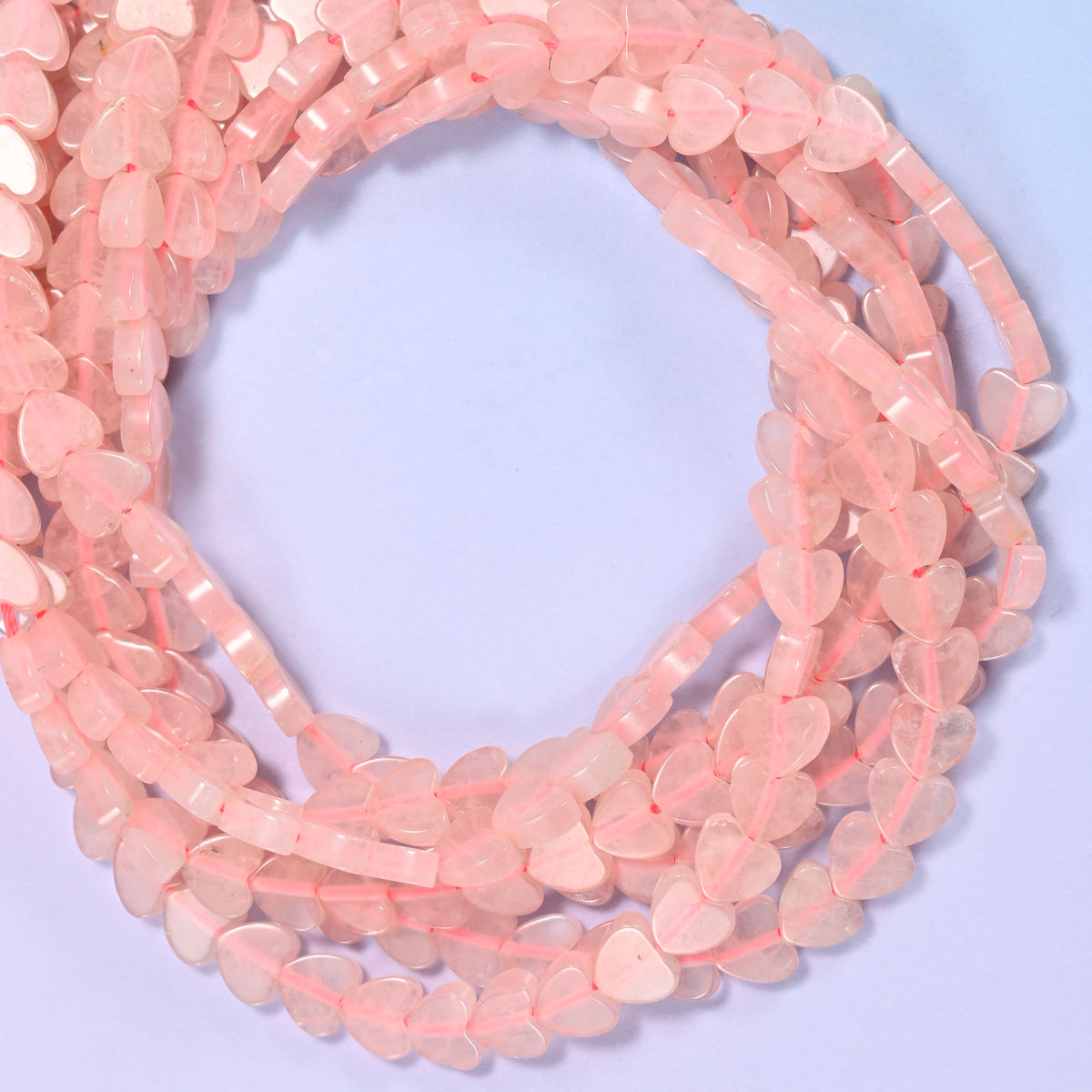 Rose Quartz flat heart beads, close view of the coiled strands in soft pink