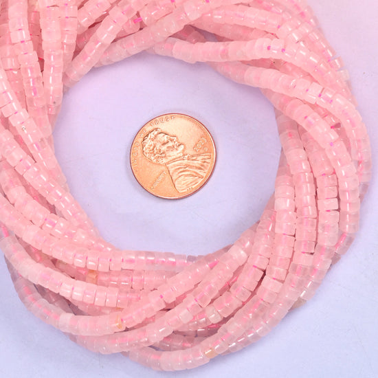 Rose Quartz smooth heishi disc bead strands coiled around a US penny for size reference