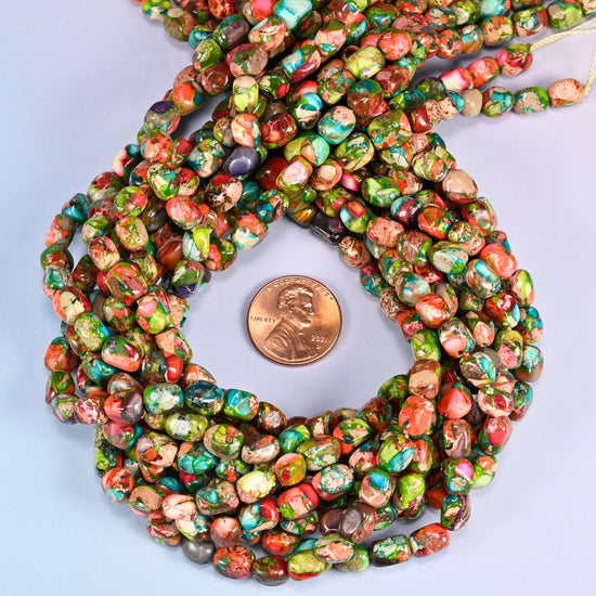 Dyed Sea Sediment Jasper nugget bead strands coiled around a US penny for size reference
