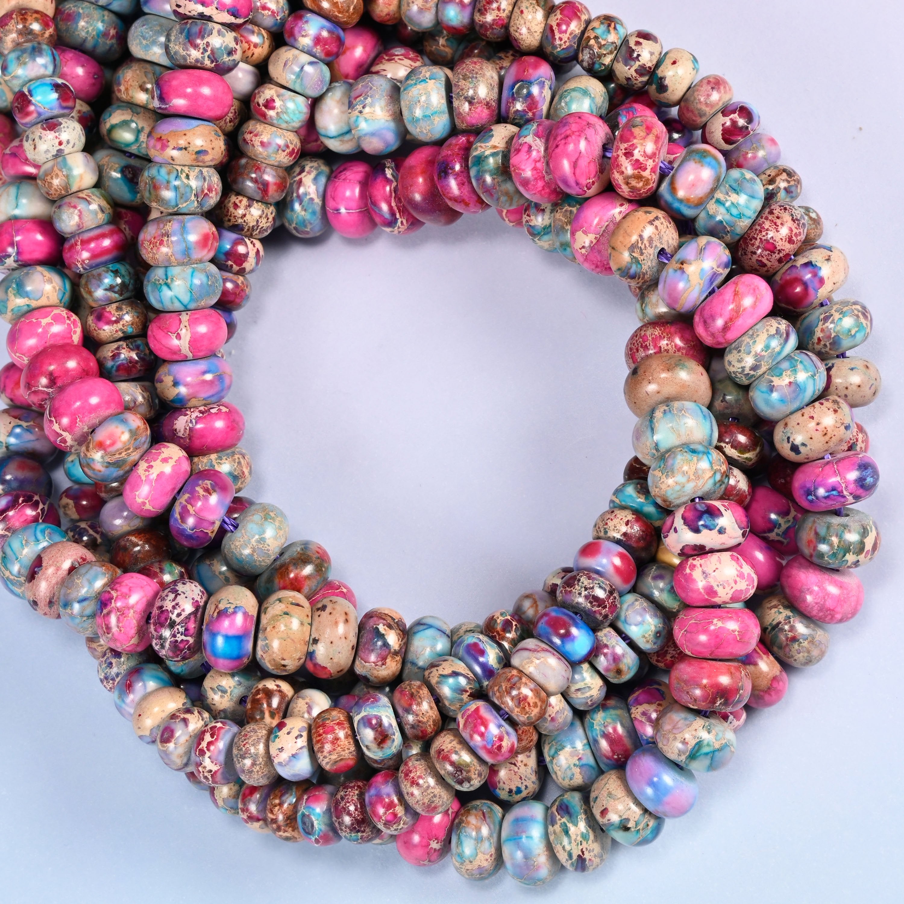 Dyed Sea Sediment Jasper rondelle beads, close view of the coiled strands mixing magenta, purple and pale blue