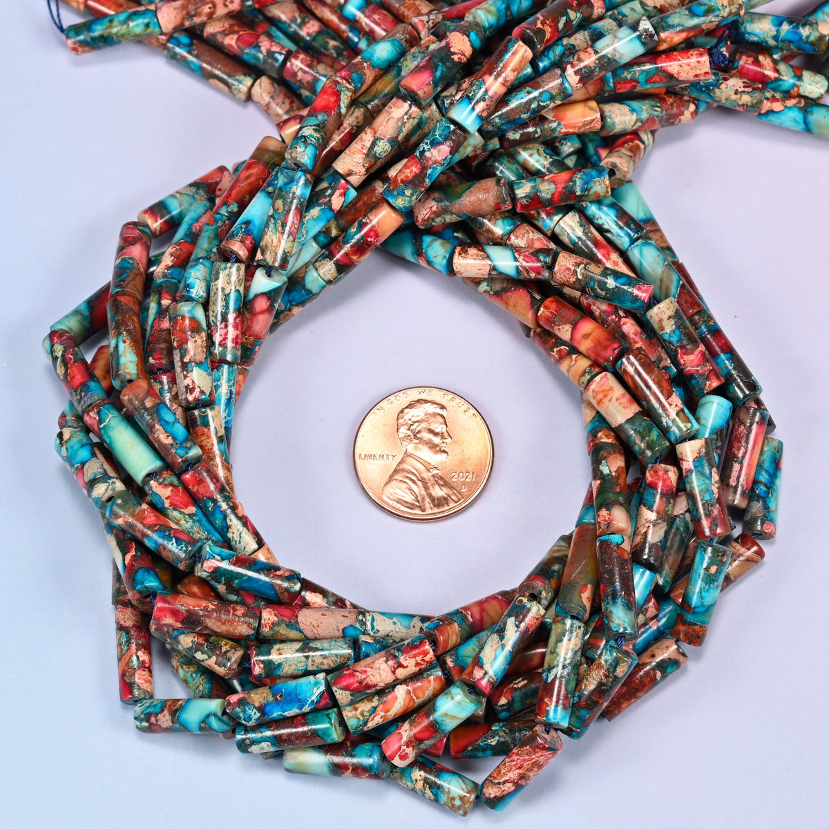 Sea Sediment Jasper tube bead strands coiled around a US penny for size reference