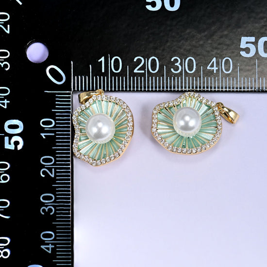 Two shell pearl charms in pale green enamel with a white pearl centre and clear pave edge, shown front and angled, beside a millimetre ruler for scale