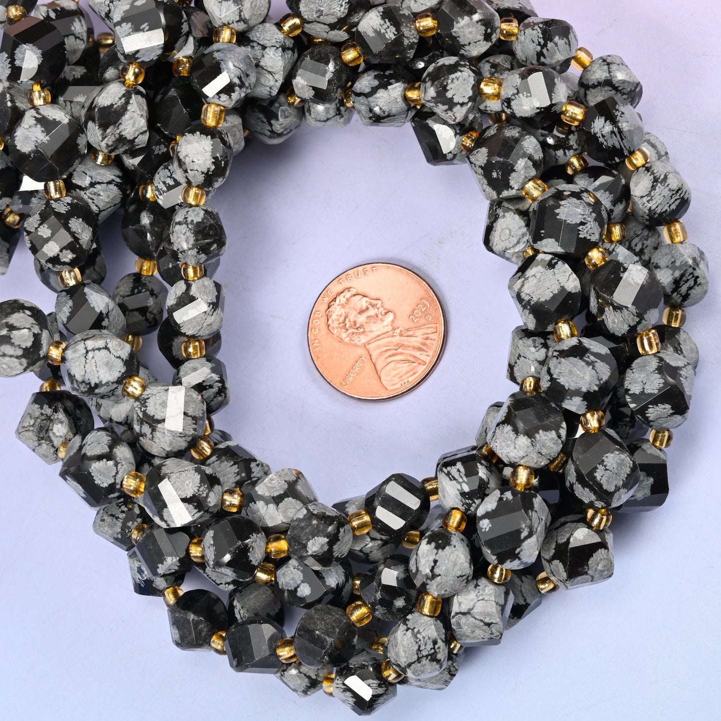 Snowflake Jasper faceted spiral twist bead strands coiled around a US penny for size reference