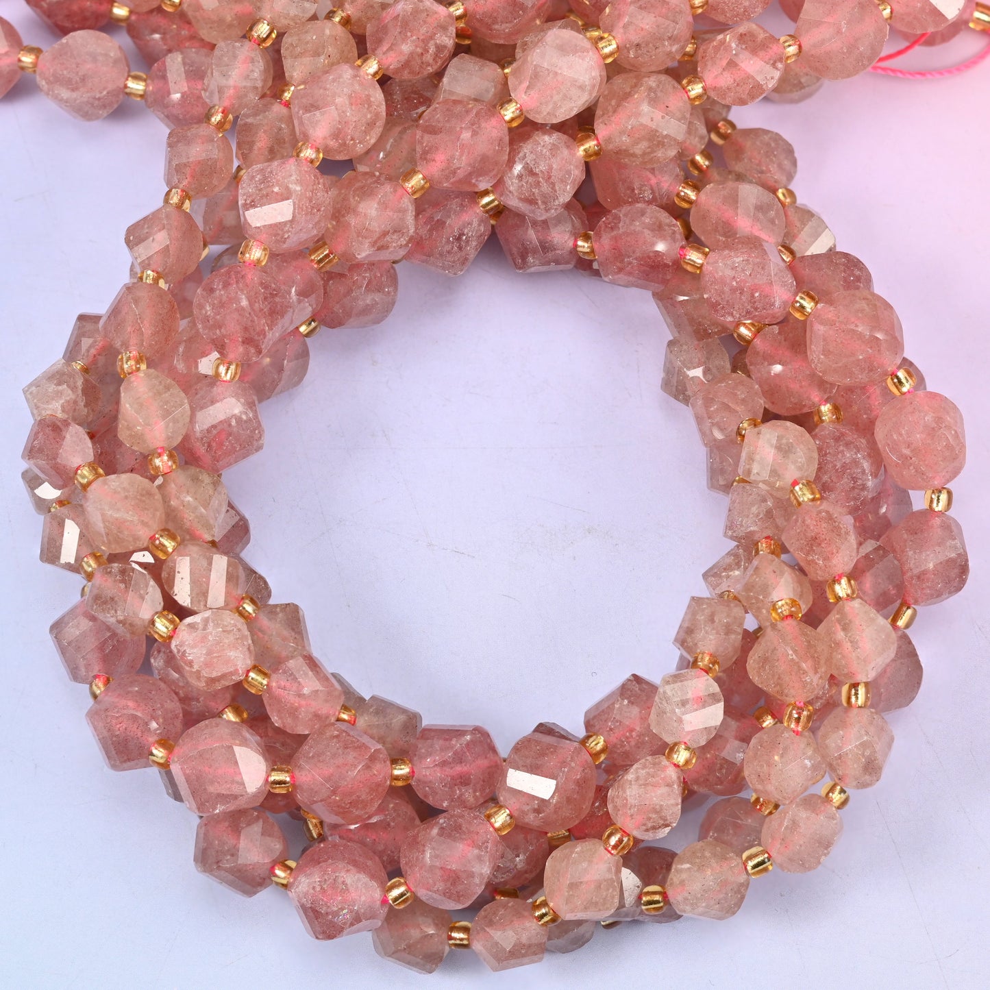 Strawberry Quartz faceted spiral twist beads, close view of the coiled strands showing the dusty rose-red colour