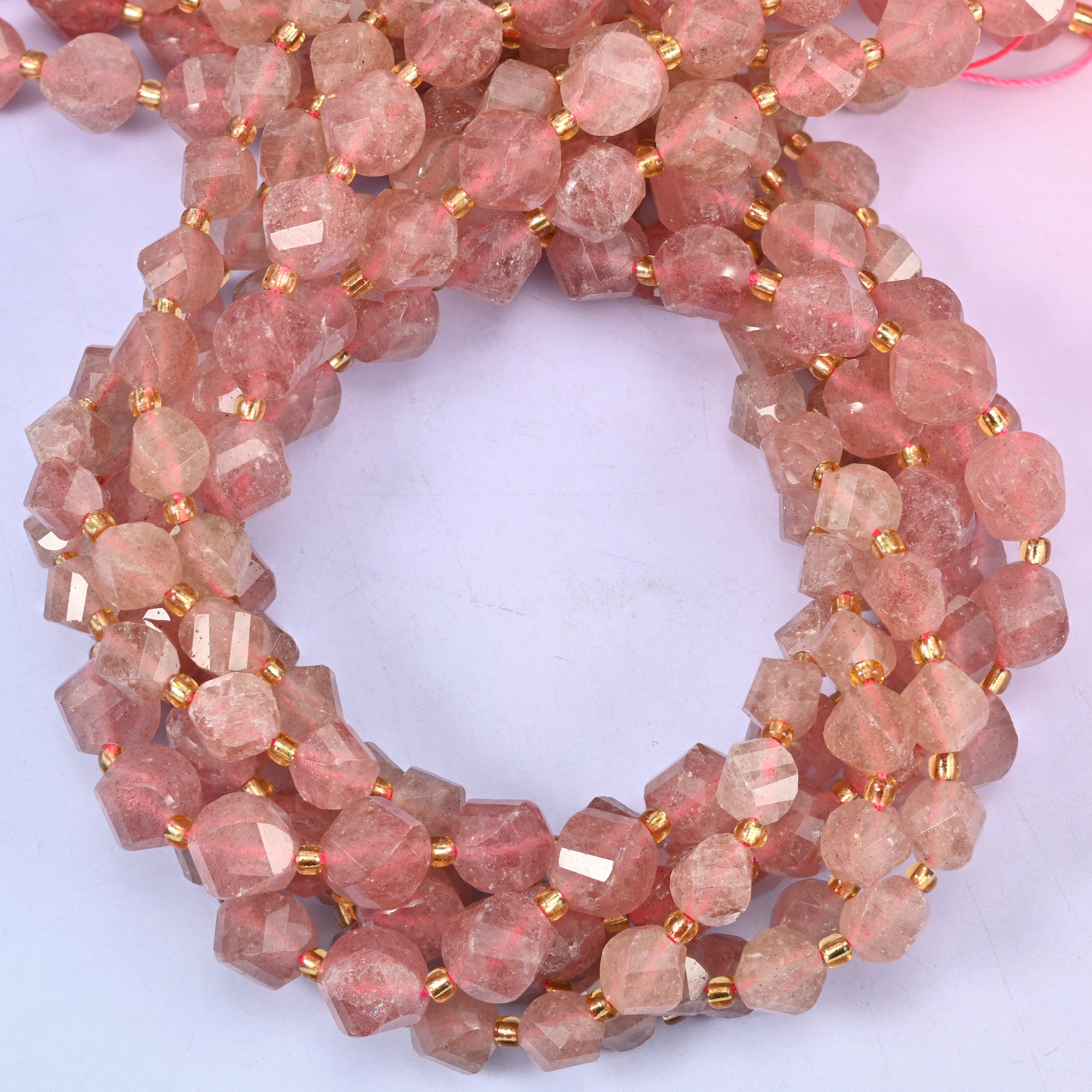 Strawberry Quartz faceted spiral twist beads, close view of the coiled strands showing the dusty rose-red colour